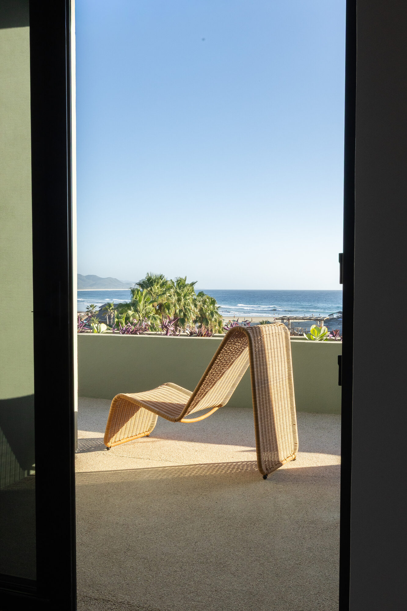 A chair on the balcony looking out over the beach and the Pacific