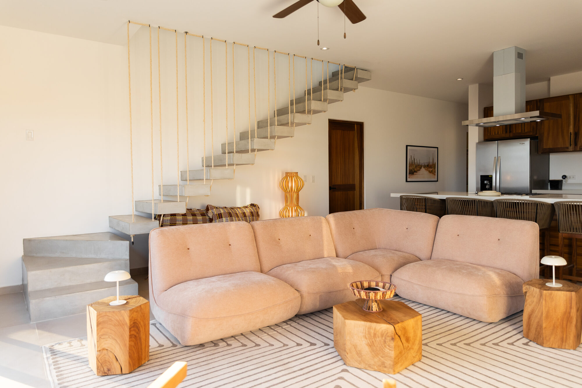 The living room sofa with cushions, facing the windows