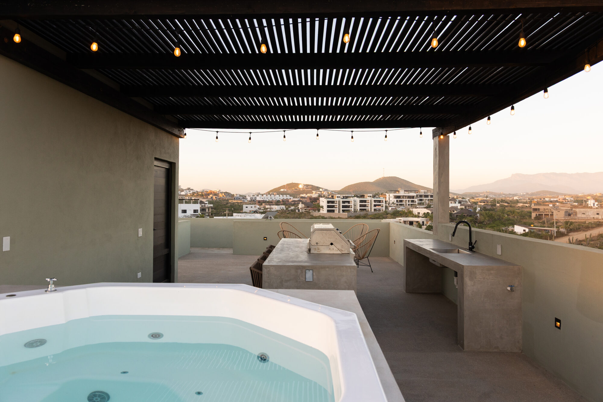 The rooftop terrace with its soaking tub and built-in outdoor kitchen, hills beyond at sunset