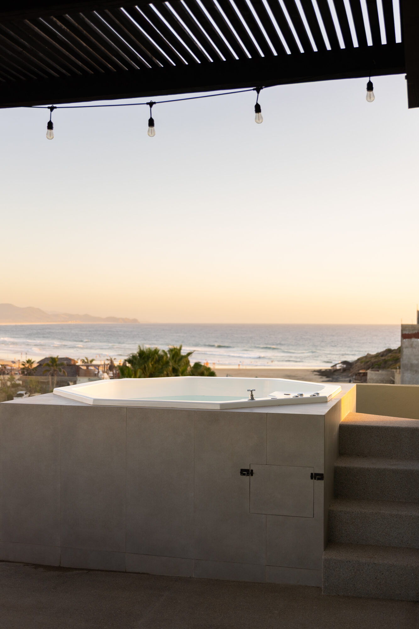 The soaking tub on the private rooftop with string lights above