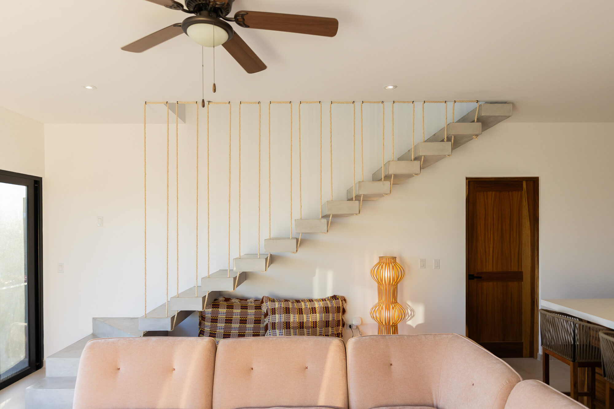 The stair leading up through the home, pale wood treads against white plaster