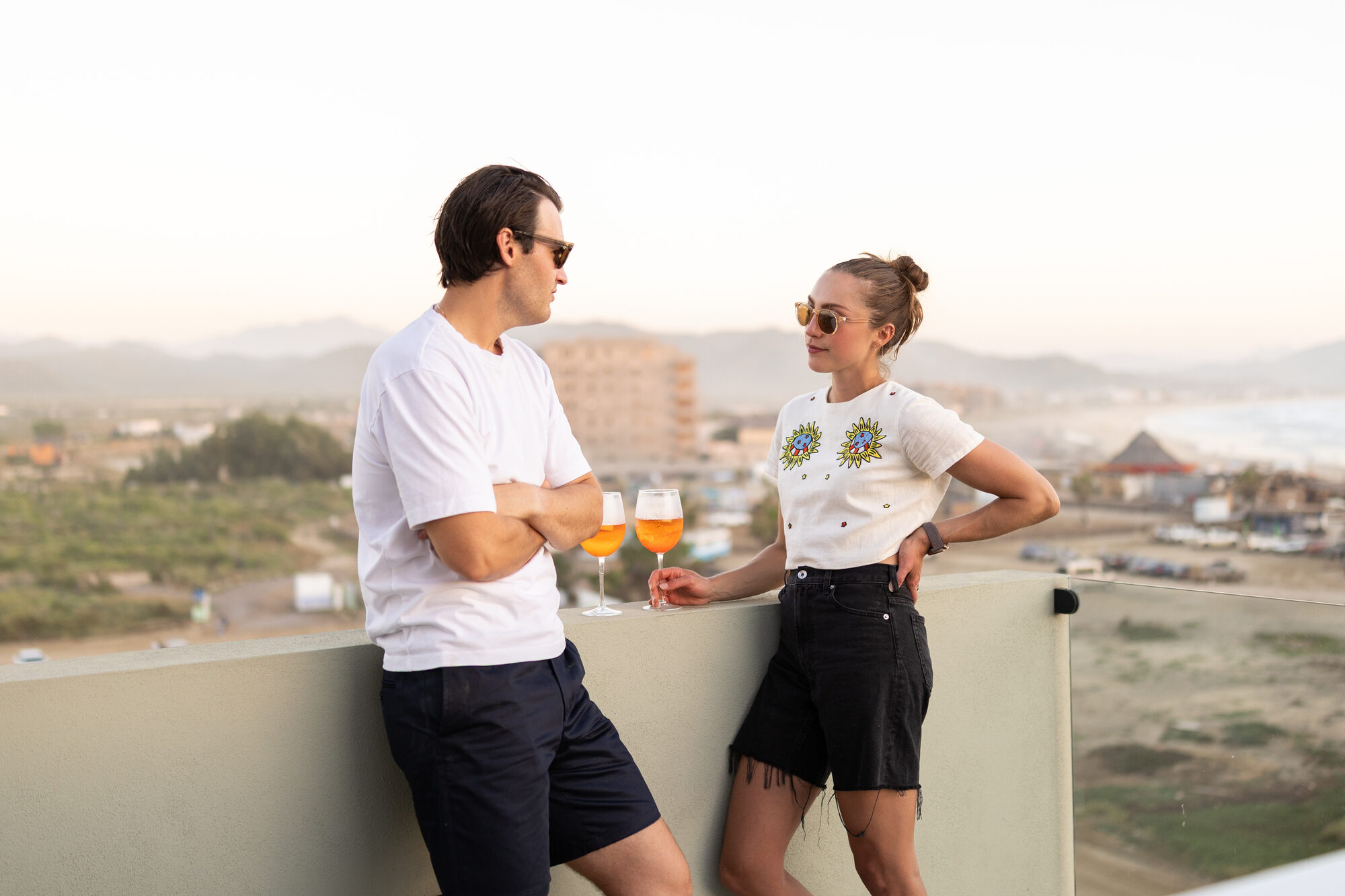 Two people on the terrace at sunset, looking toward the water